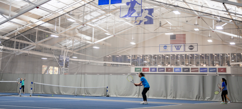 Students playing tennis in an indoor court